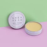 Belly Butter als offene Dose vor farbigem Hintergrund