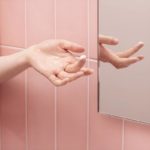 Finger mit etwas Belly Butter auf der Fingerspitze vor einem Spiegel