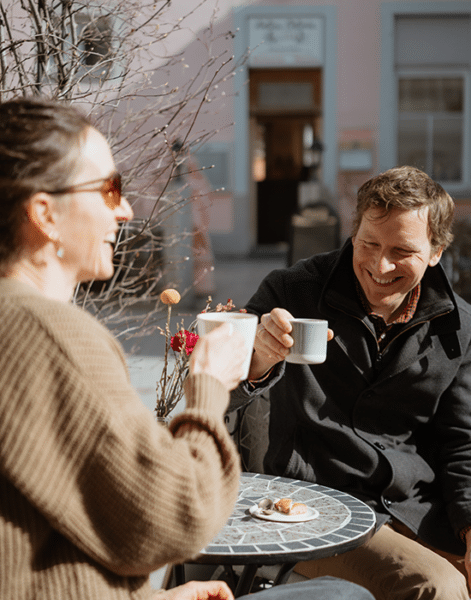 ein Paar sitzt draussen an der Sonne und trinkt Kaffee