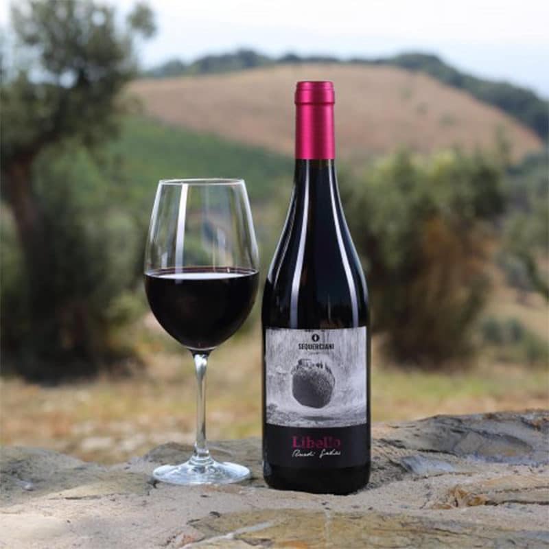 Libello Rotwein mit eingeschenktem Glas vor Olivenbaum