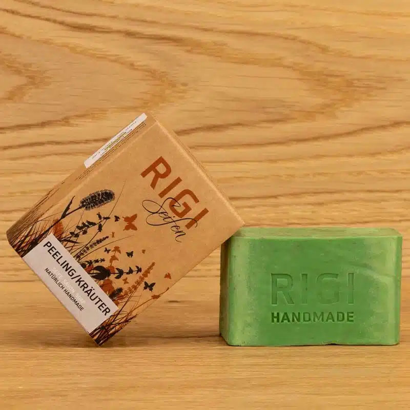 Verpackung der Rigi Seifen in der Variante Peeling / Kräuter. Die Verpackung ist an die grüne Seife angelehnt. In di Seife ist RIGI HANDMADE eingeprägt.