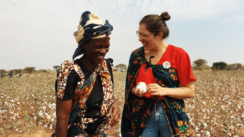 Zwei Frauen stehen auf einem Baumwollfell und lachen.